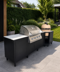 Schwarze Outdoor-Küche Koala Modell 1 mit Napoleon Einbau-Gasgrill, sandfarbenem Kamado und heller Dekton-Arbeitsplatte auf einer Terrasse