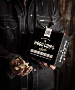 Holy Smoke Wood Chips Apfel – Räucherchips in der Hand vor dunklem Hintergrund