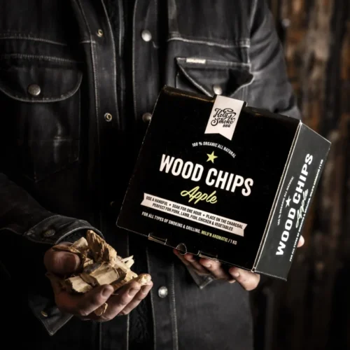 Holy Smoke Wood Chips Apfel – Räucherchips in der Hand vor dunklem Hintergrund