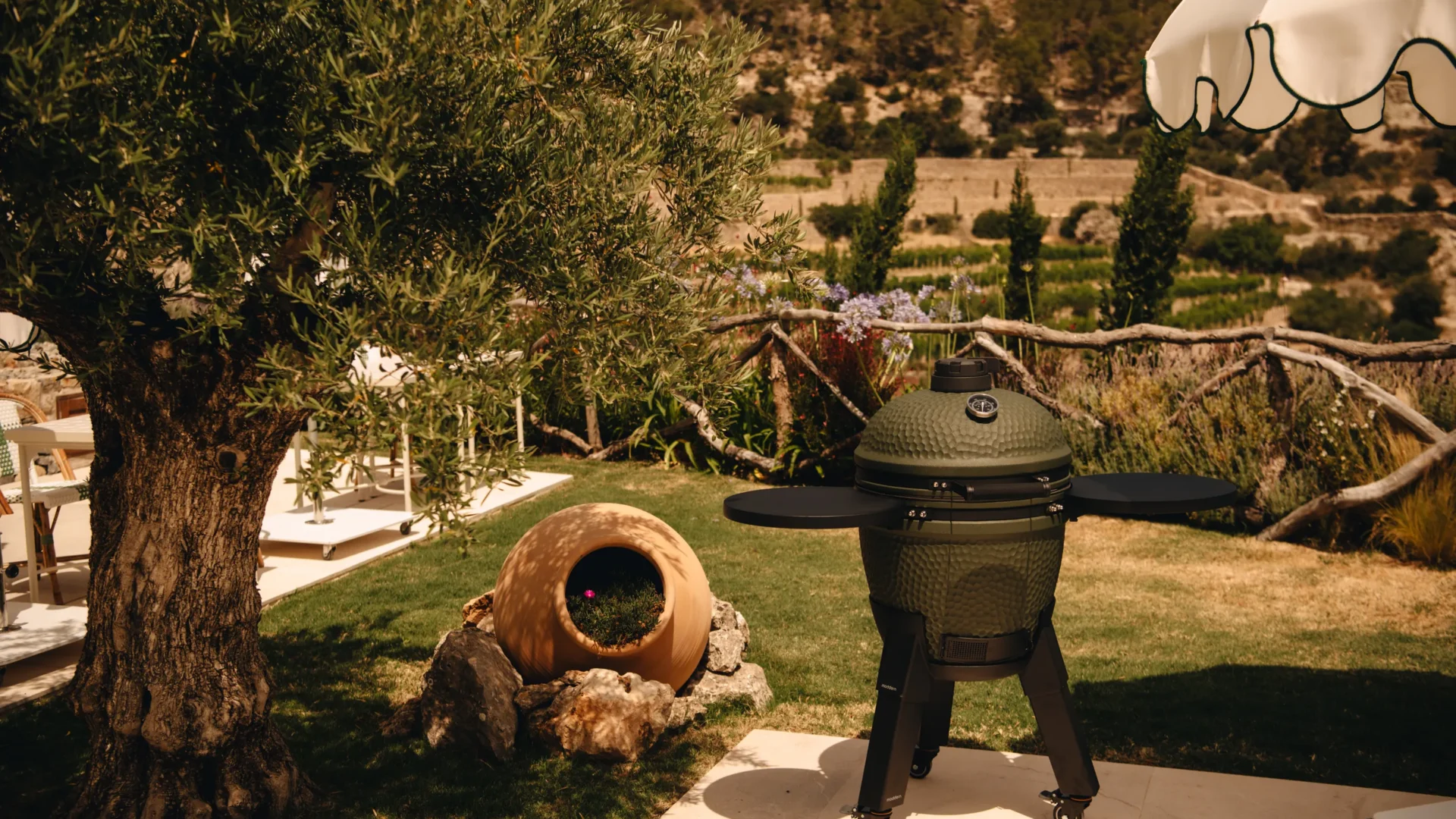 Moddern Kamado-Grill im Garten unter einem Olivenbaum
